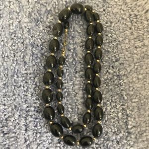 Black beaded necklace with gold chain and clasp.